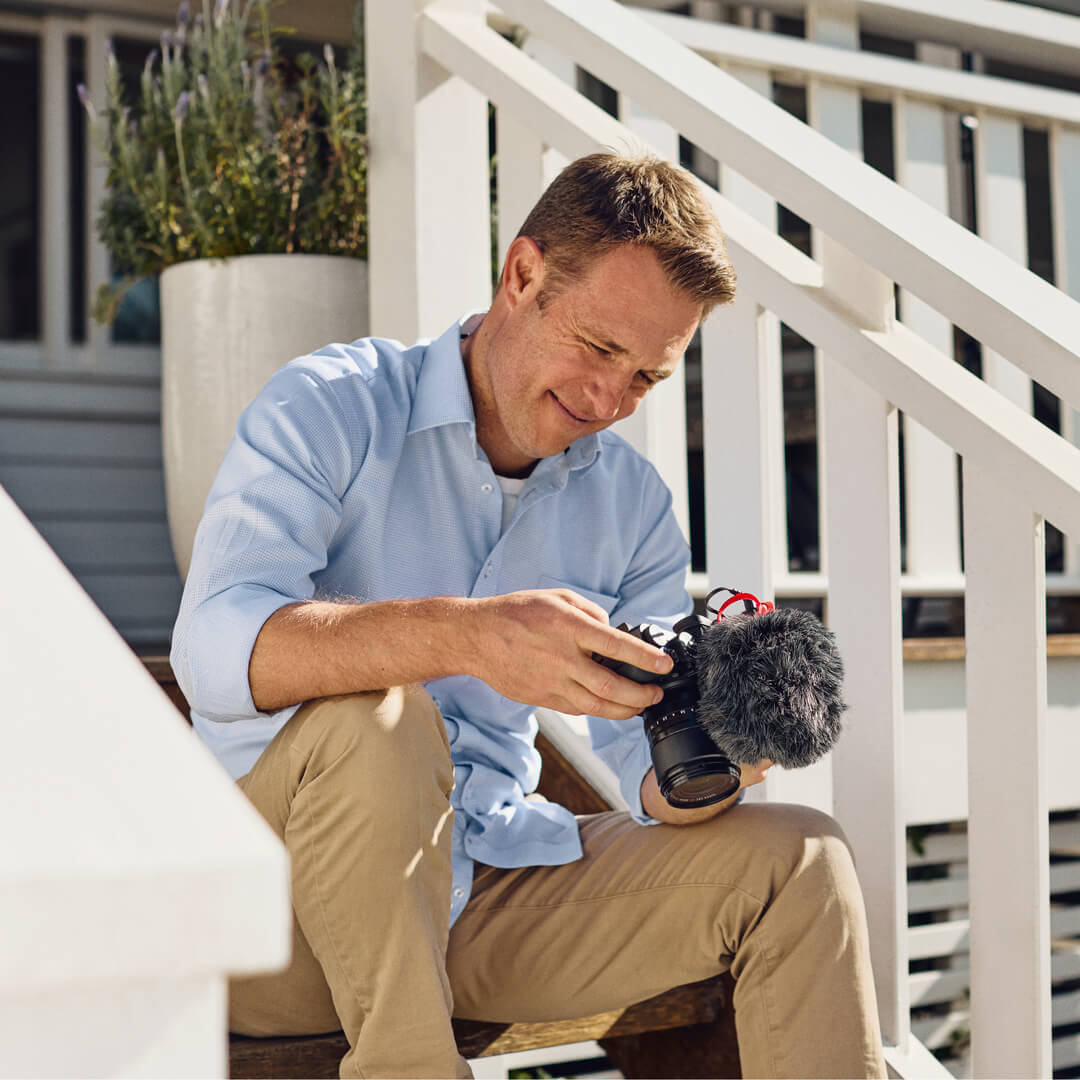 VideoMicro II on a handheld camera outdoors with its furry windshield fitted and red HELIX mount visible.
