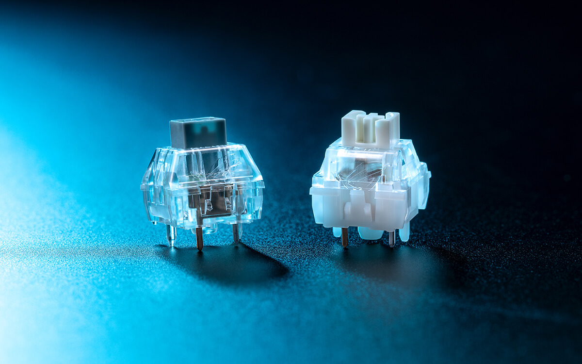 Close-up of two ROG NX hot-swappable mechanical switches, translucent housing, on a blue-lit surface